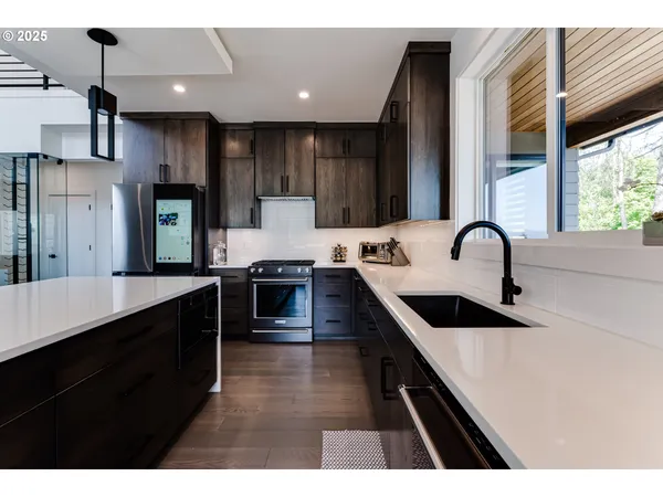 a kitchen with kitchen island granite countertop a sink a counter top space stainless steel appliances and cabinets