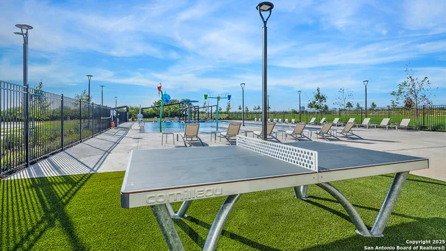 a view of swimming pool with outdoor seating and trees in the background