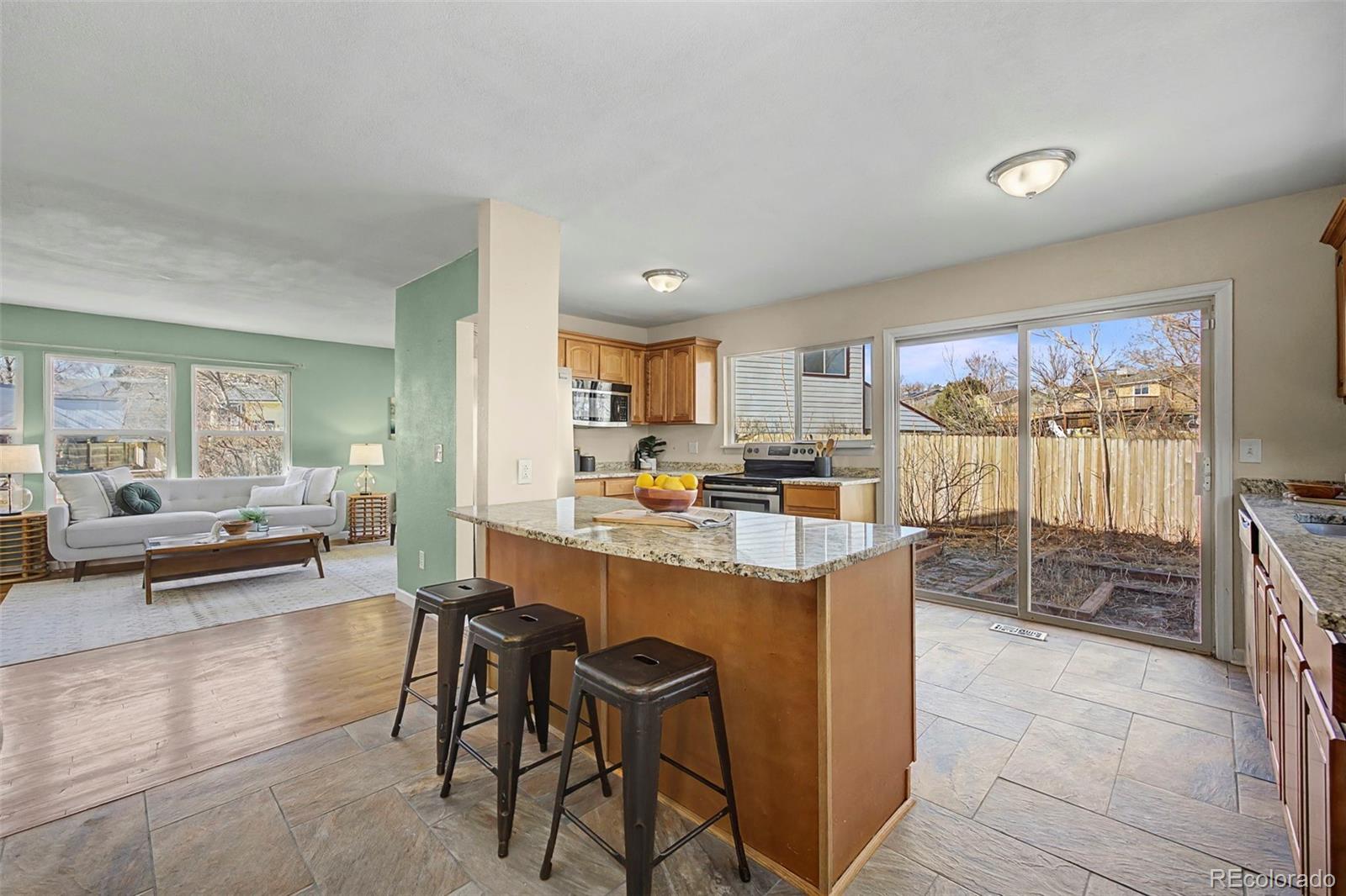 4394 South Van Gordon Way Morrison, CO 80465 - Photo 6 of 20 a kitchen with stainless steel appliances kitchen island granite countertop a table and chairs in it
