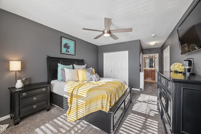 a bedroom with a bed and a flat tv screen on dresser