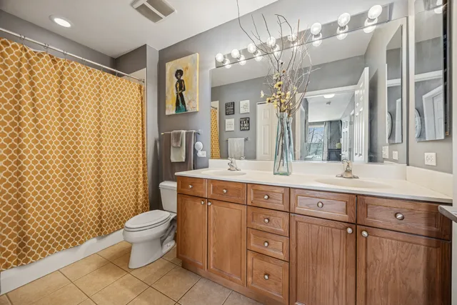 a spacious bathroom with a granite countertop sink a toilet a mirror a vanity and shower