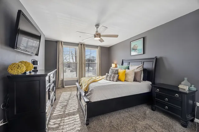 a bedroom with a bed mirror on desk and a window