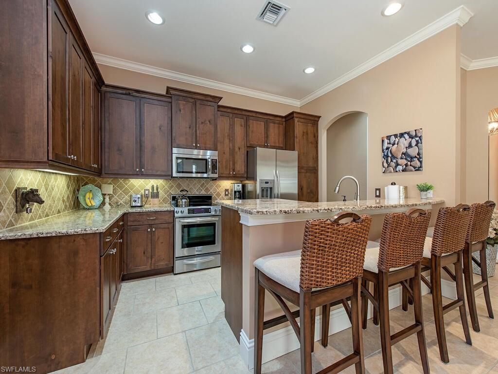 8000 Cordoba Place Naples, FL 34113 - Photo 5 of 16 a kitchen with a table chairs microwave and cabinets