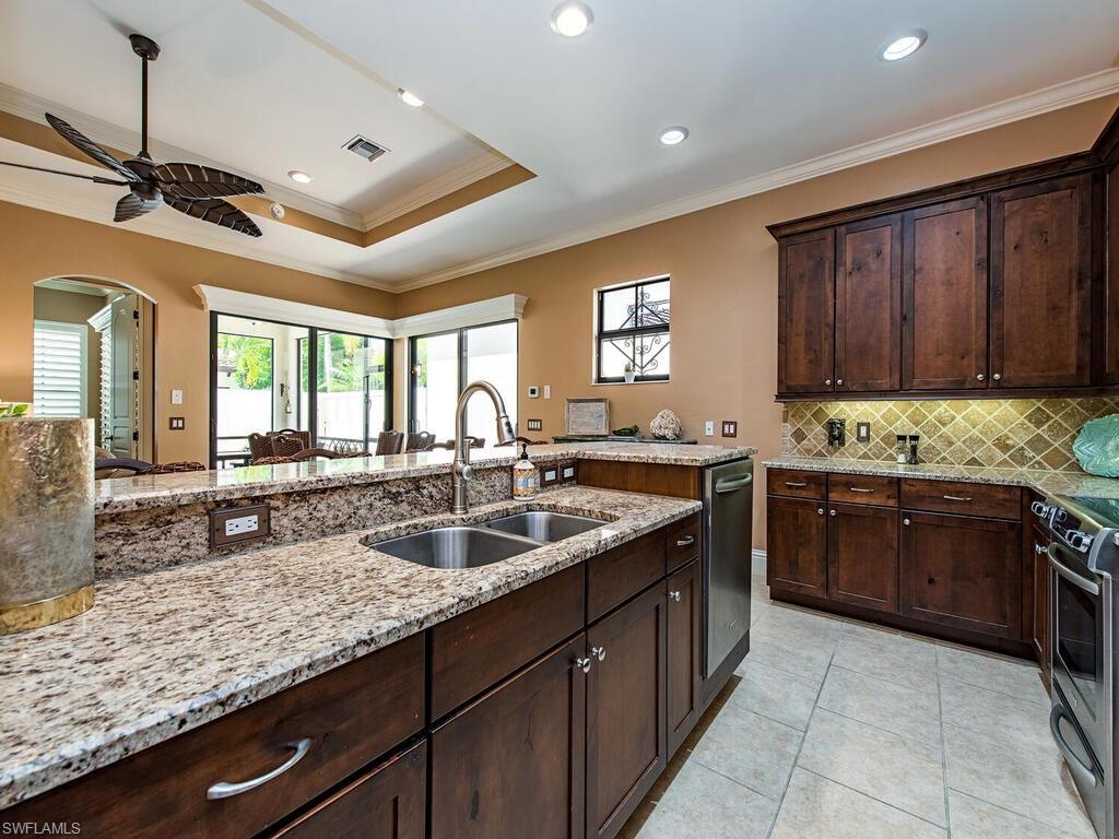 8000 Cordoba Place Naples, FL 34113 - Photo 6 of 16 a kitchen with granite countertop stainless steel appliances a sink stove and cabinets