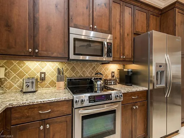 a kitchen with granite countertop a stove microwave and refrigerator