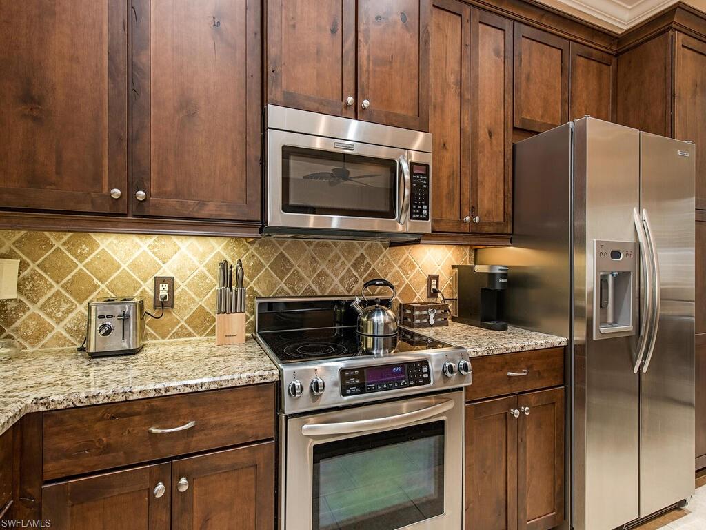 8000 Cordoba Place Naples, FL 34113 - Photo 7 of 16 a kitchen with granite countertop a stove microwave and refrigerator