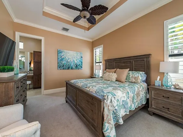 a bedroom with a bed a mirror on dresser and a chandelier