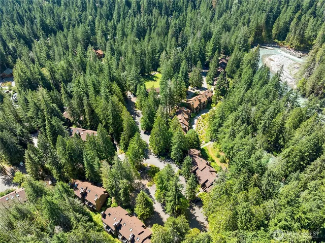 an aerial view of residential house with outdoor space and trees all around