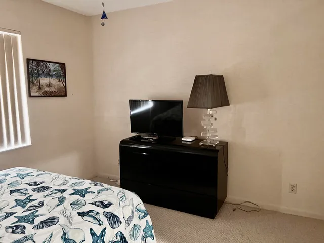 a bedroom with a bed and a flat tv screen on a dresser