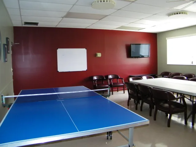 a room with pool table and lots of potted plants