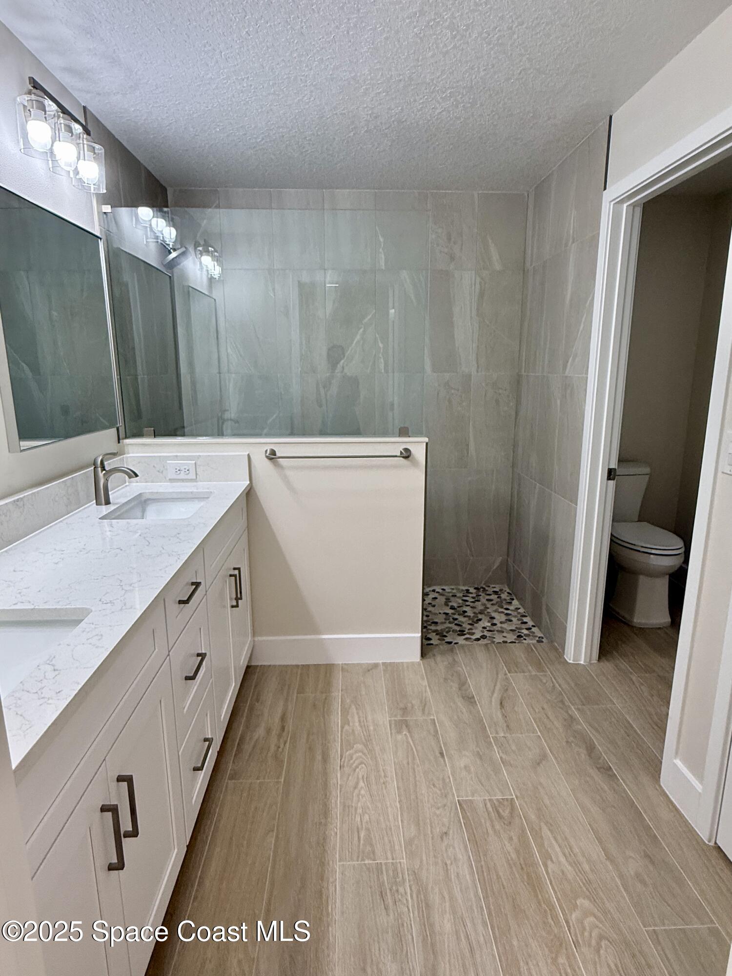 581 Toynbee Road Palm Bay, FL 32908 - Photo 15 of 25 a spacious bathroom with a sink a toilet a mirror and shower