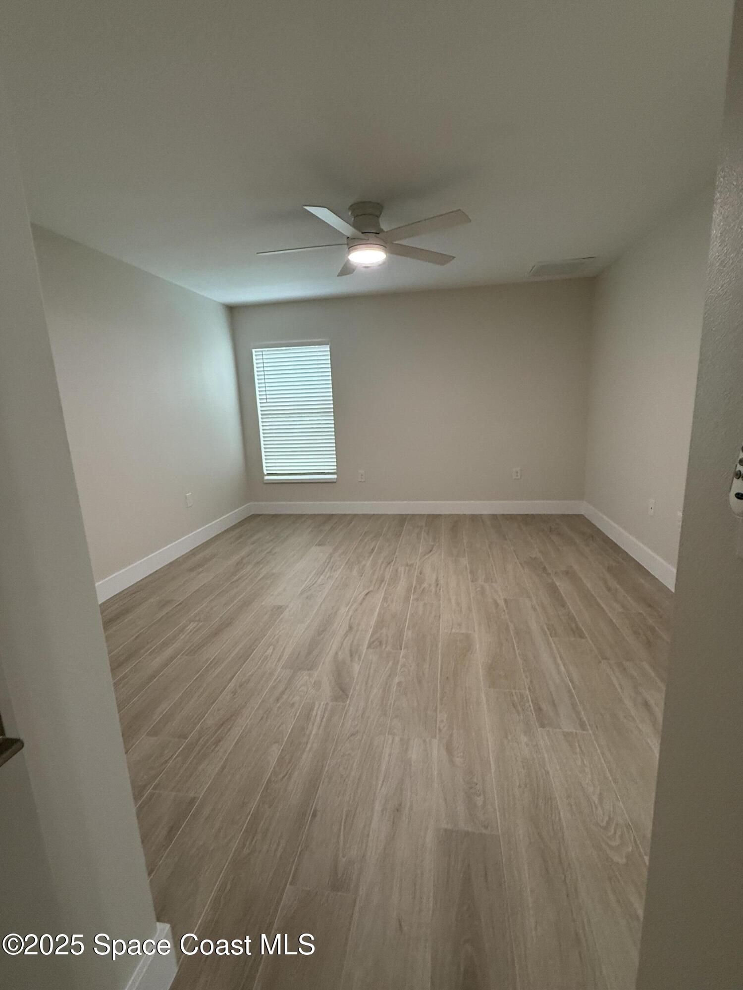 581 Toynbee Road Palm Bay, FL 32908 - Photo 18 of 25 an empty room with wooden floor and windows