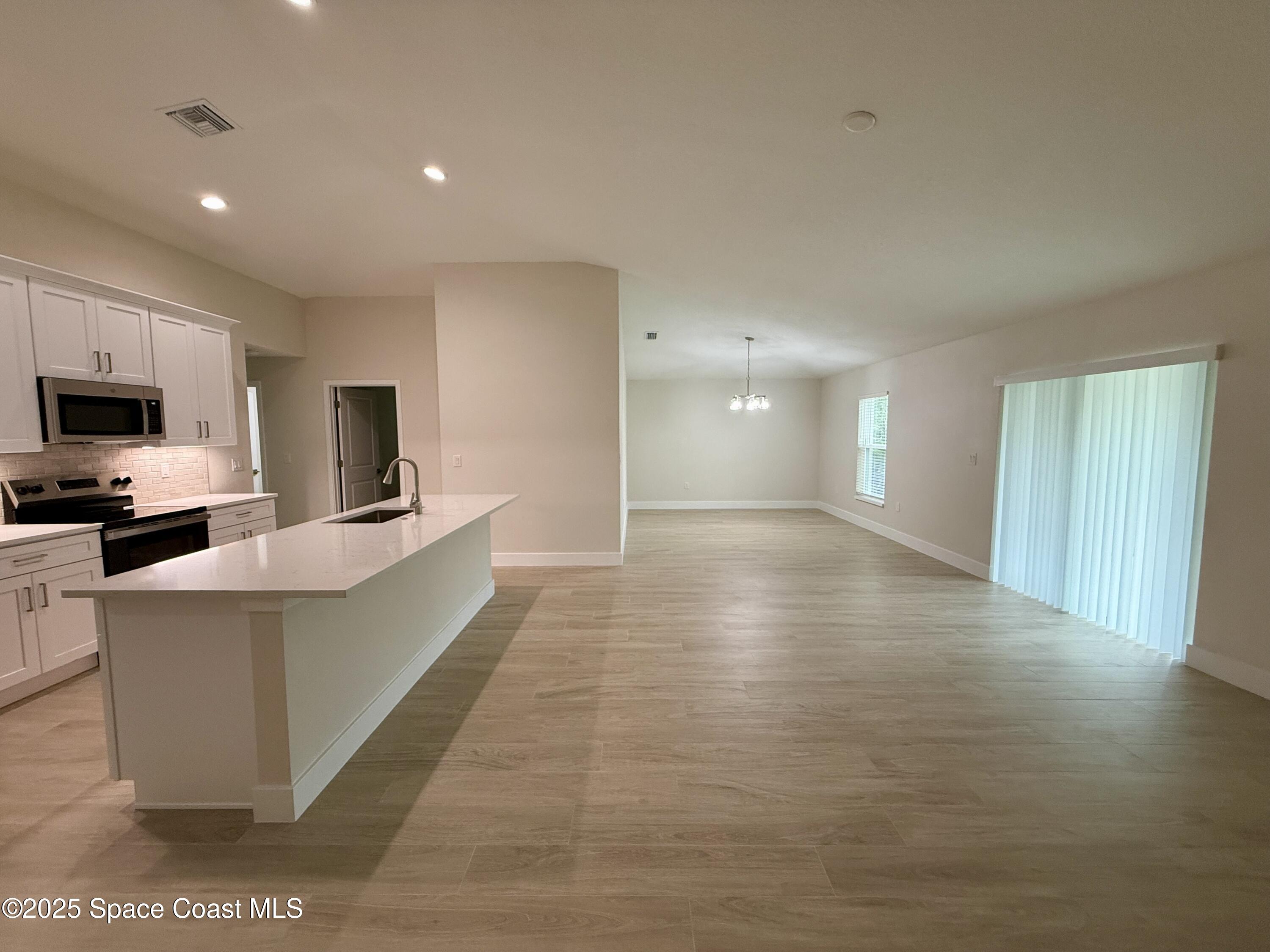 581 Toynbee Road Palm Bay, FL 32908 - Photo 4 of 25 a view of a kitchen with kitchen island a sink wooden floor and black appliances