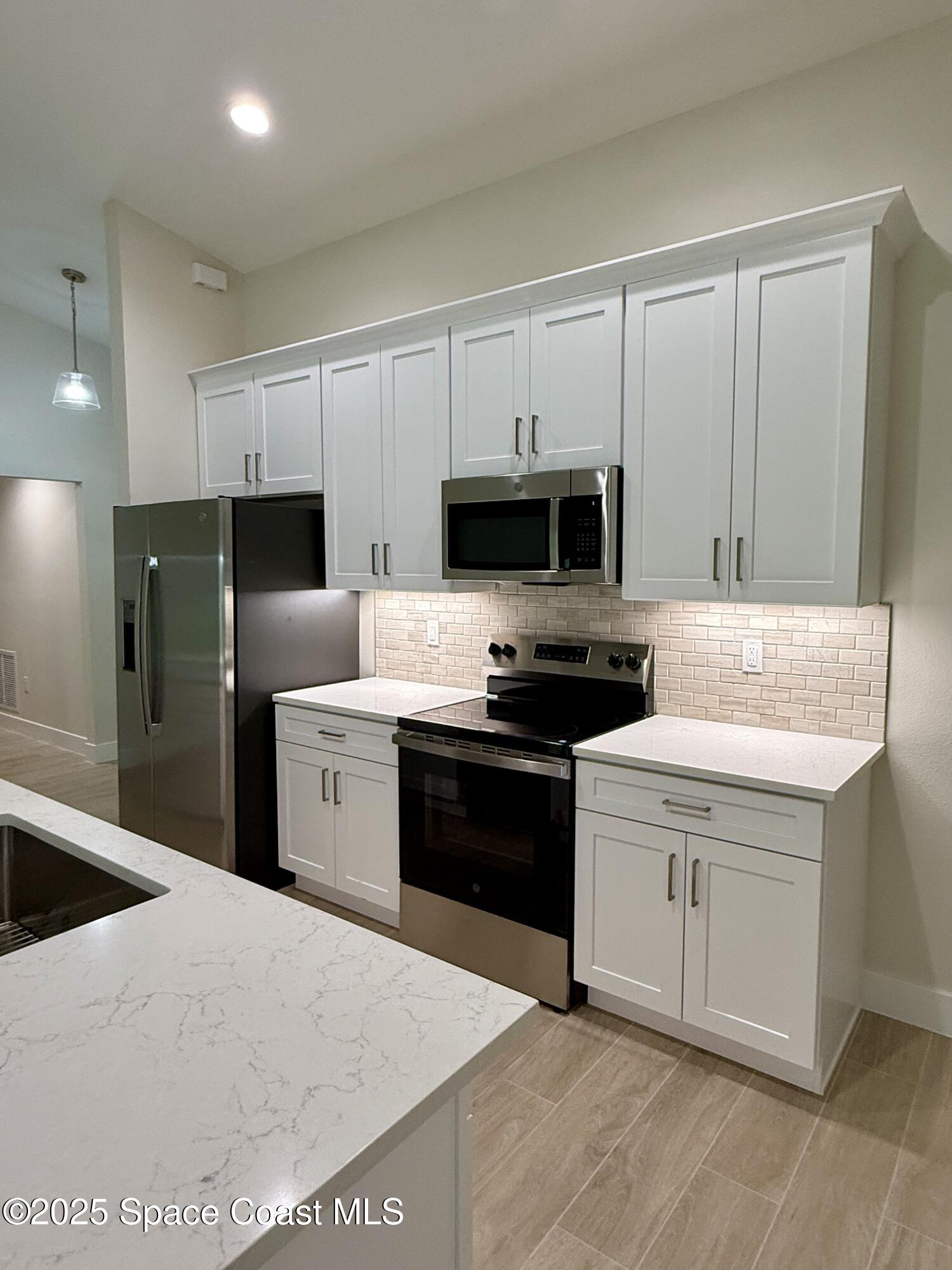 581 Toynbee Road Palm Bay, FL 32908 - Photo 6 of 25 a kitchen with a refrigerator stove and microwave