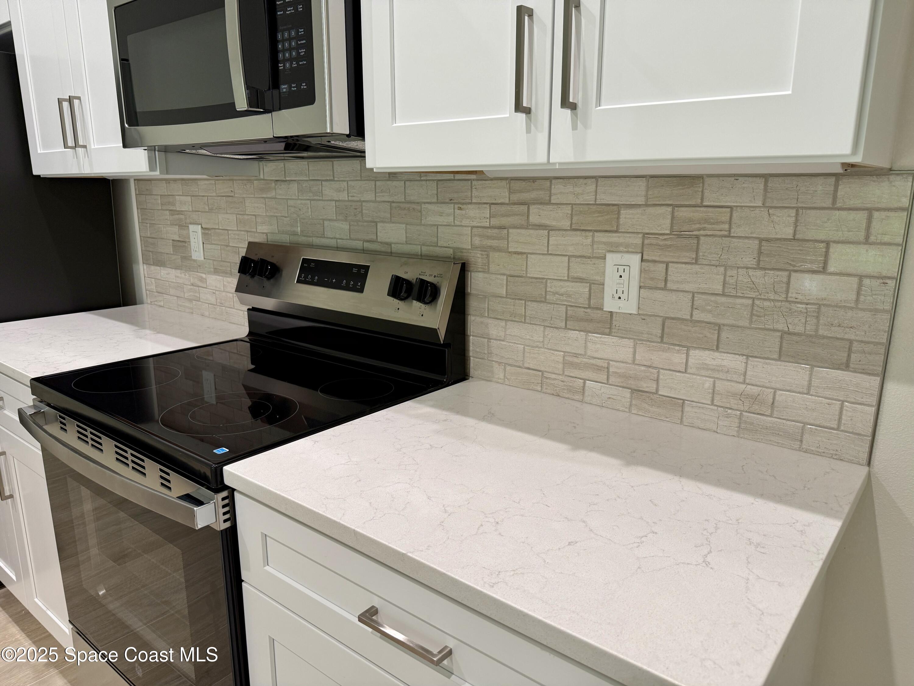 581 Toynbee Road Palm Bay, FL 32908 - Photo 10 of 25 a kitchen with granite countertop white cabinets and black appliances