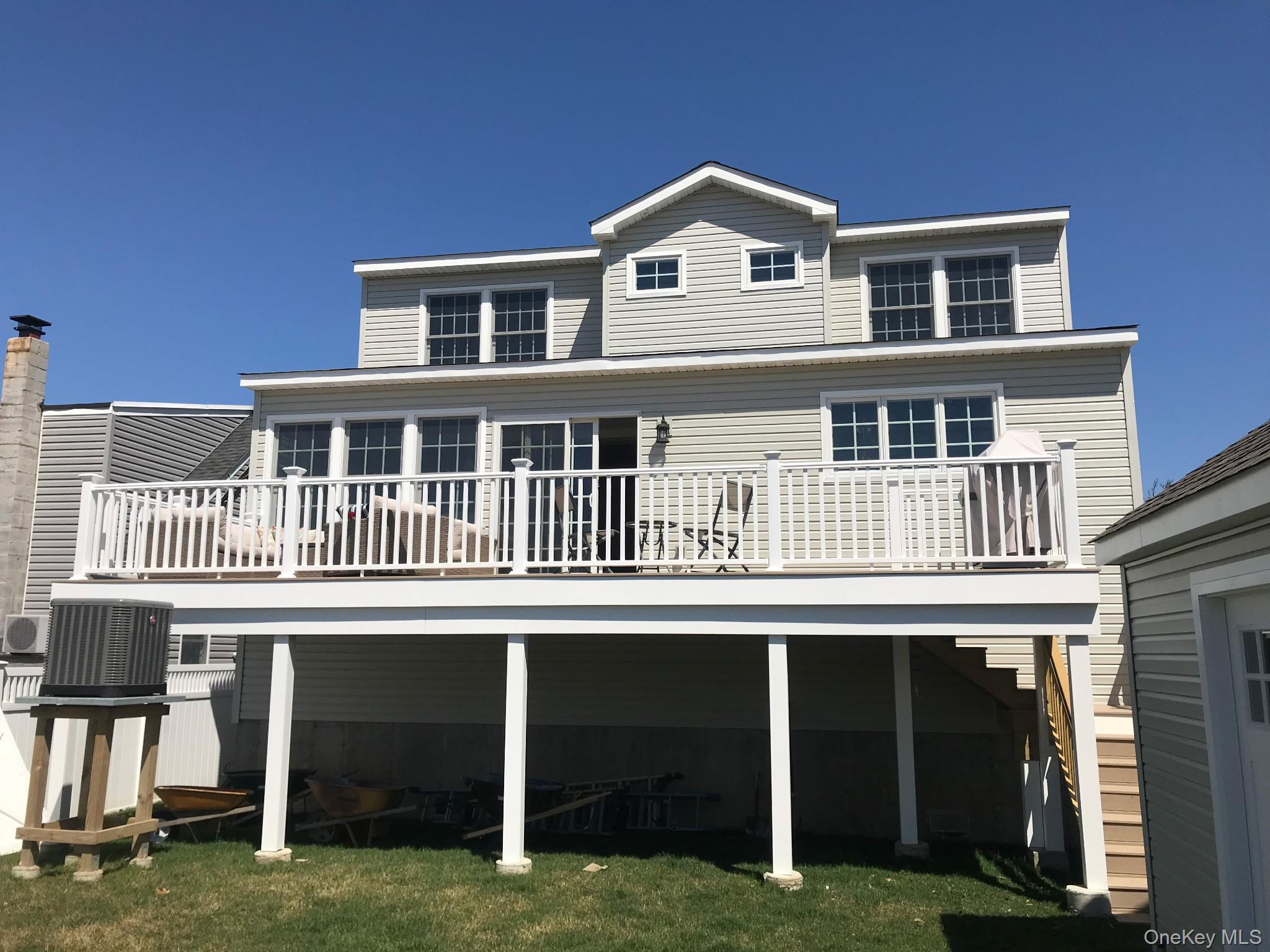 Rear view of house with a wooden deck and a lawn