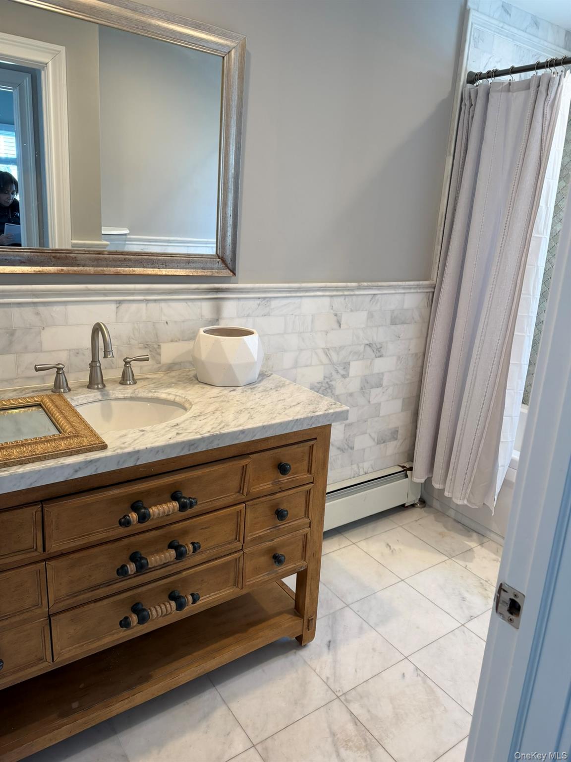 16 Cape Road Amityville, NY 11701 - Photo 12 of 27 Full bathroom with baseboard heating, vanity, a wainscoted wall, shower / tub combo with curtain, and tile walls