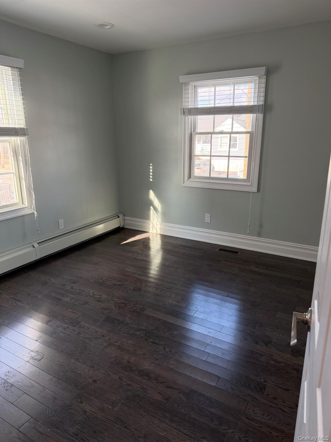 16 Cape Road Amityville, NY 11701 - Photo 13 of 27 Unfurnished room with a baseboard heating unit and dark wood finished floors