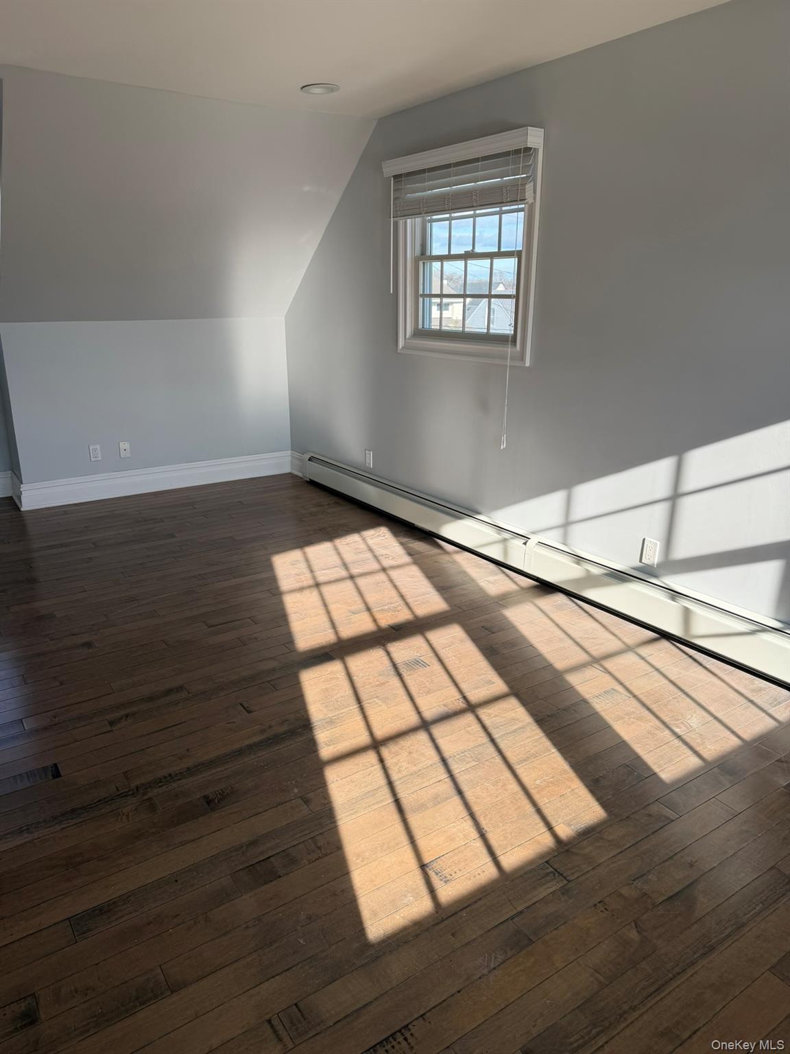 16 Cape Road Amityville, NY 11701 - Photo 14 of 27 Bonus room with a baseboard radiator, dark wood-style flooring, and vaulted ceiling