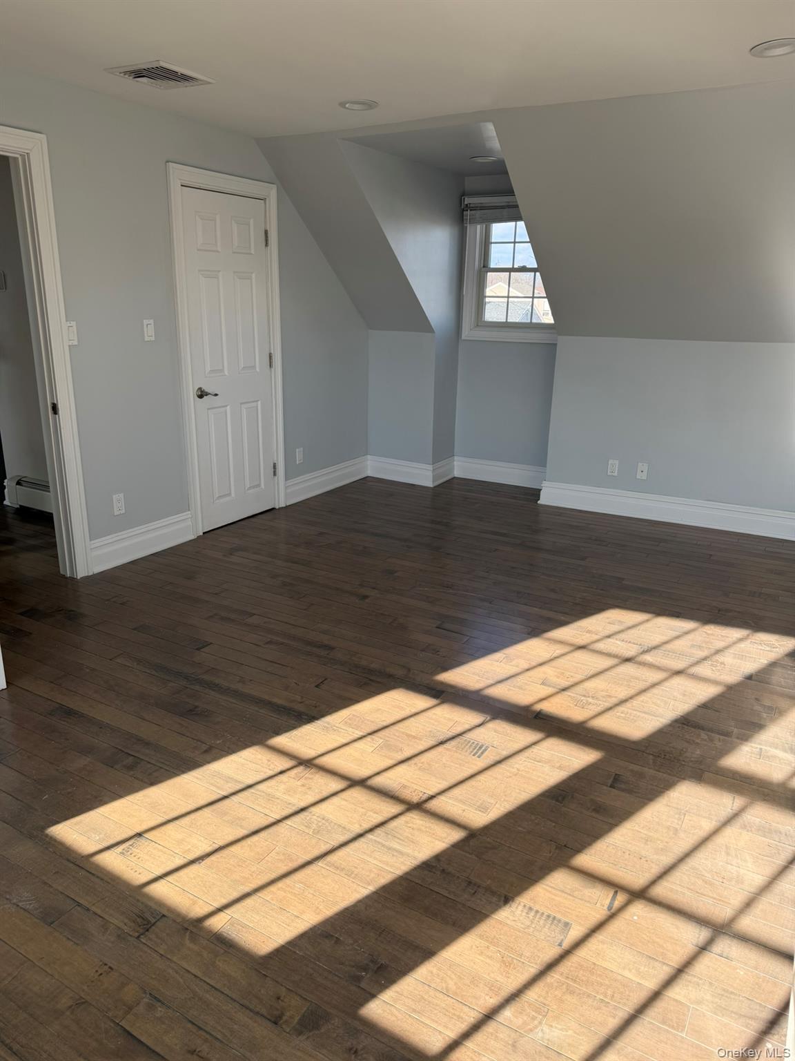 16 Cape Road Amityville, NY 11701 - Photo 15 of 27 Bonus room with dark wood finished floors and a baseboard heating unit