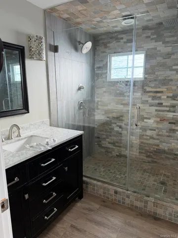 a bathroom with a granite countertop sink a mirror and shower