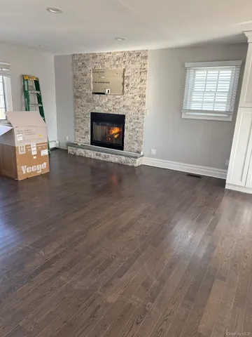 an empty room with wooden floor fireplace and windows