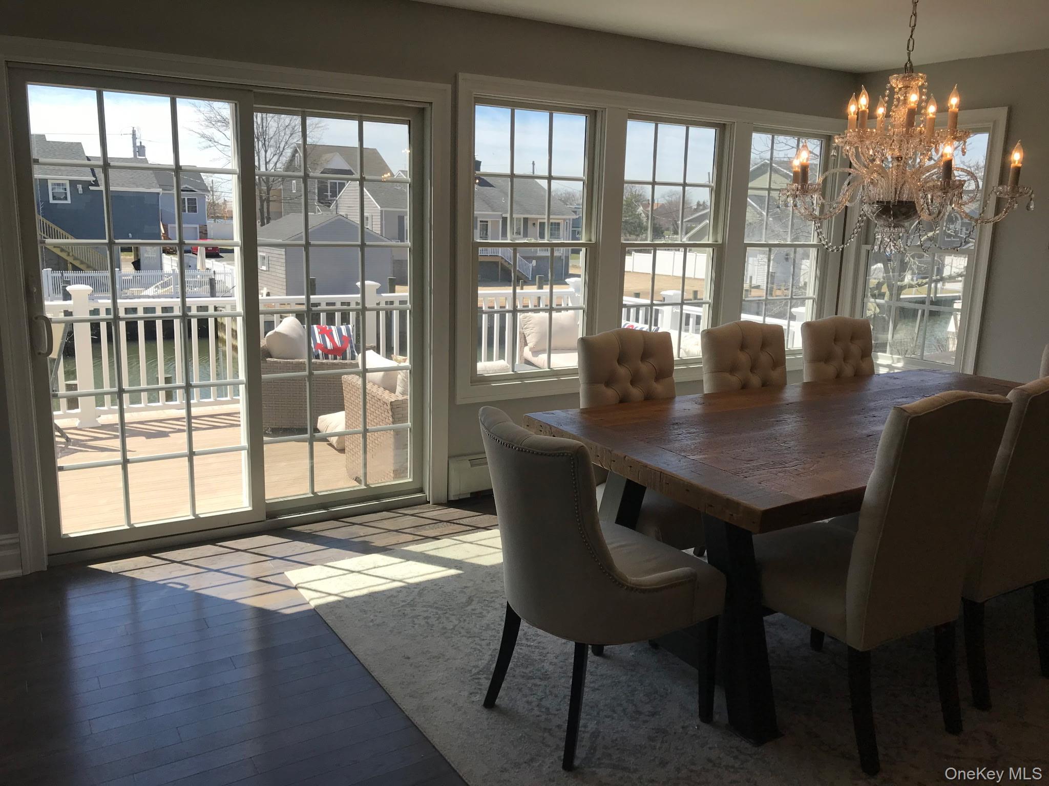 16 Cape Road Amityville, NY 11701 - Photo 6 of 27 Dining room featuring a chandelier, a water view, a baseboard heating unit, and a residential view