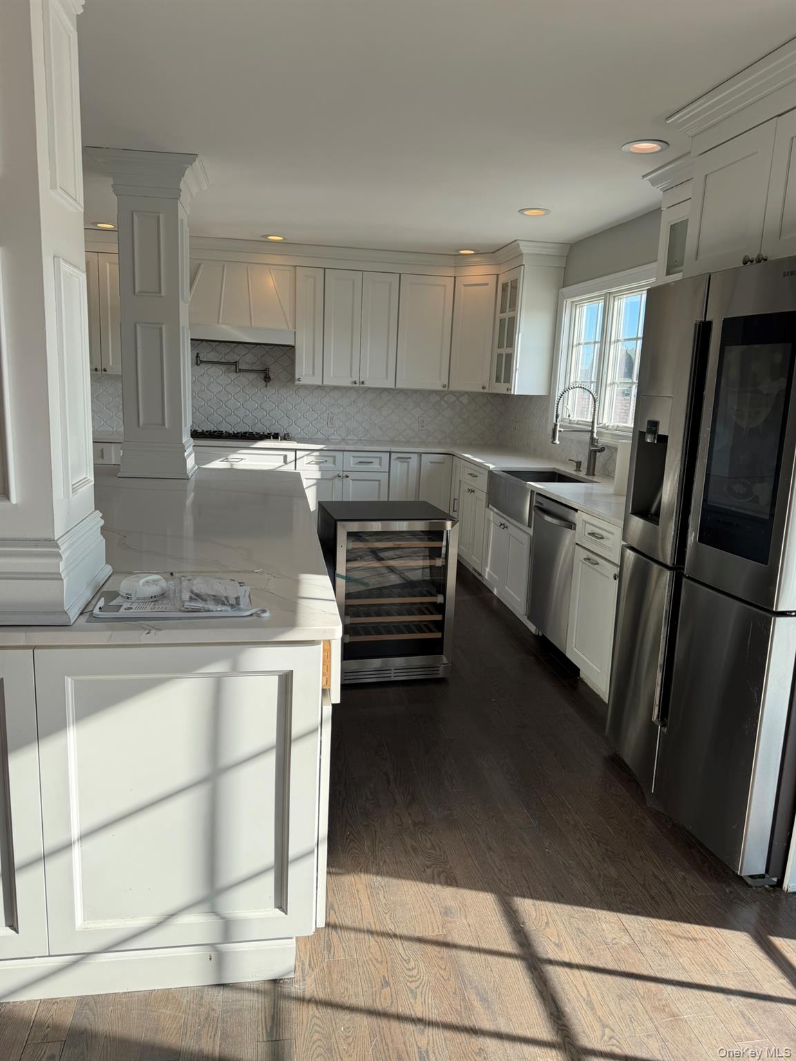 16 Cape Road Amityville, NY 11701 - Photo 9 of 27 Kitchen with appliances with stainless steel finishes, beverage cooler, white cabinetry, light stone counters, and recessed lighting