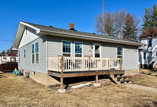 a view of a house with a wooden deck and furniture