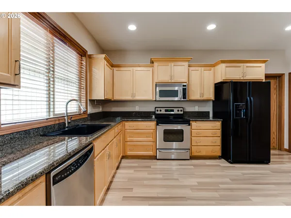 a kitchen with stainless steel appliances kitchen island granite countertop a stove a refrigerator and a sink