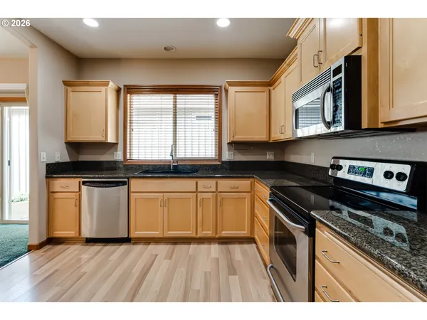 a kitchen with granite countertop wooden cabinets stove and sink