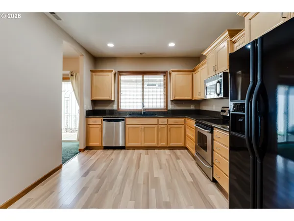 a kitchen with granite countertop a refrigerator stove top oven and sink