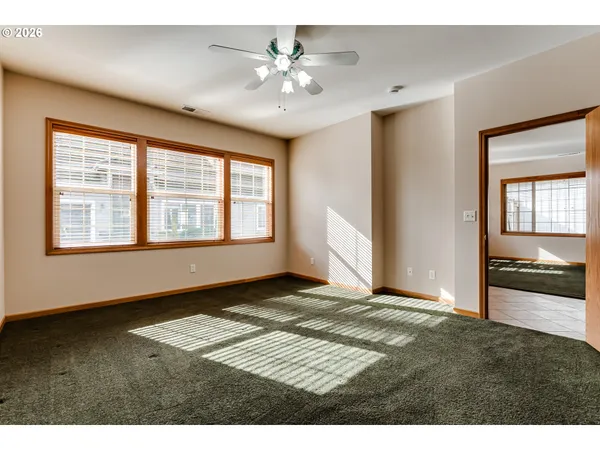 a view of an empty room with window and a kitchen