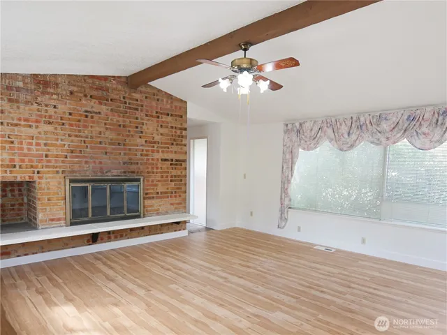 a view of an empty room with wooden floor and a fireplace