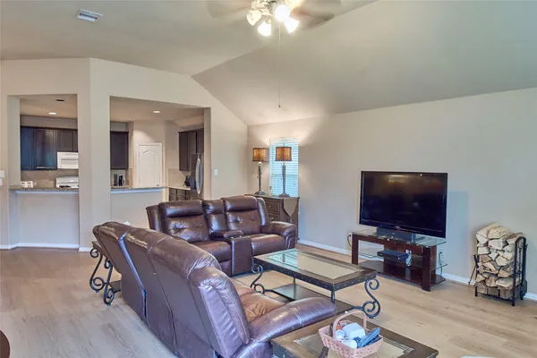 a living room with furniture a flat screen tv and wooden floor