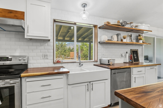 4270 River Road Oakley, UT 84055 - Photo 17 of 46 Kitchen featuring a double basin farmhouse sink, wood-finish countertops, stainless steel appliances, white subway tile backsplash, and open shelving