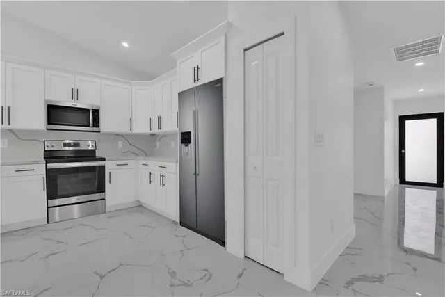 a kitchen with stainless steel appliances a refrigerator sink and white cabinets