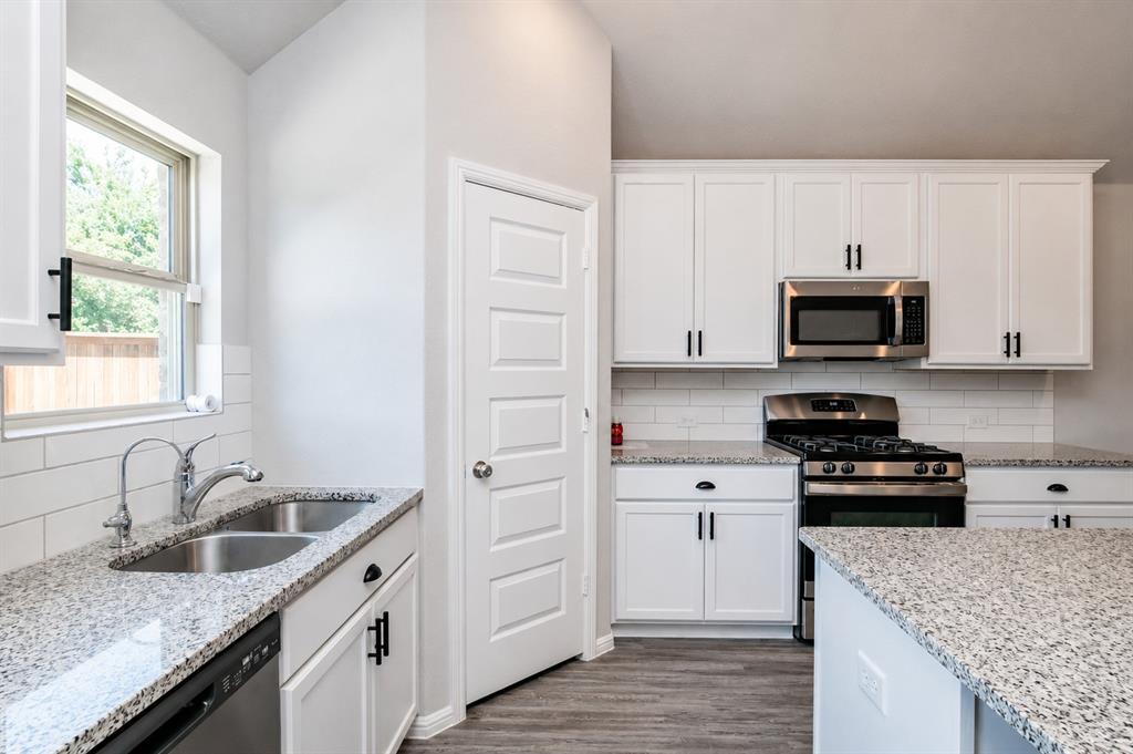 3344 Duncan Way Corinth, TX 76210 - Photo 13 of 38 Kitchen featuring granite countertops, white shaker cabinetry with matte black hardware, stainless steel appliances, and wood-finish flooring