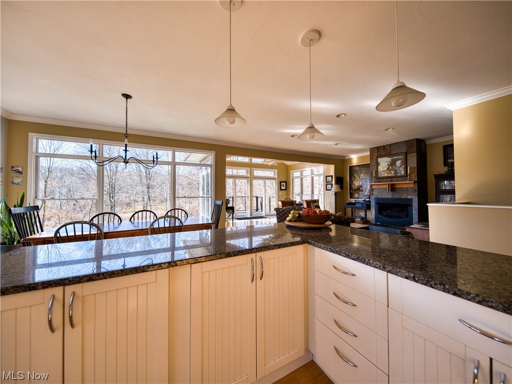 13730 Sperry Road Novelty, OH 44072 - Photo 11 of 31 Kitchen with dark stone countertops, hanging light fixtures, a large fireplace, an inviting chandelier, and ornamental molding