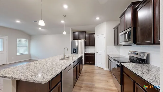 a kitchen with stainless steel appliances kitchen island granite countertop a refrigerator and a stove top oven