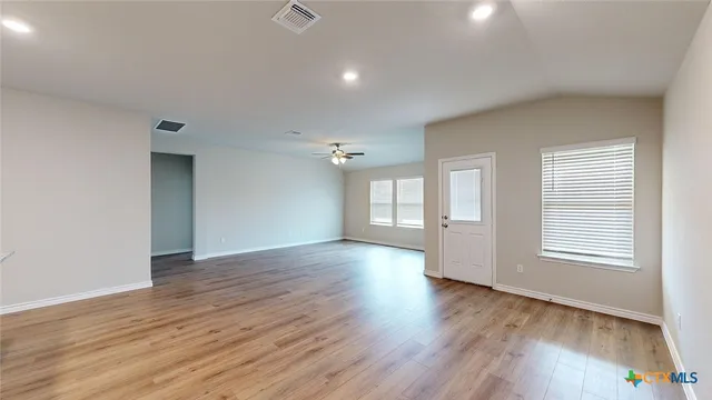 a view of an empty room with wooden floor and a window