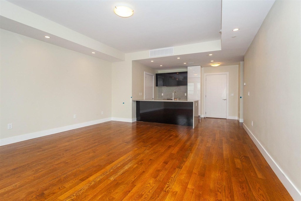 906 East 2nd Street, Unit 106 Boston, MA 02127 - Photo 6 of 14 an empty room with wooden floor and entrance