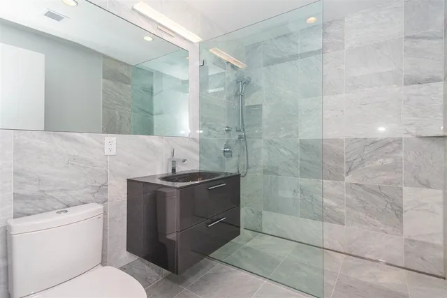 a bathroom with a granite countertop sink a toilet and a shower