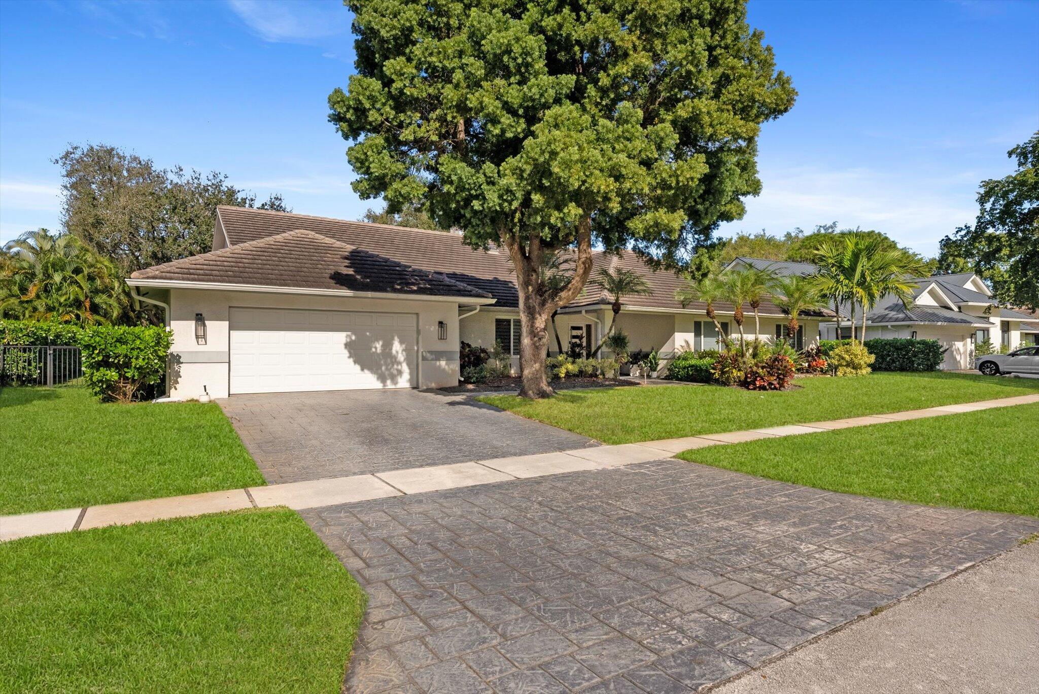 4429 Woodfield Boulevard Boca Raton, FL 33434 - Photo 59 of 61 a front view of a house with a yard and garage