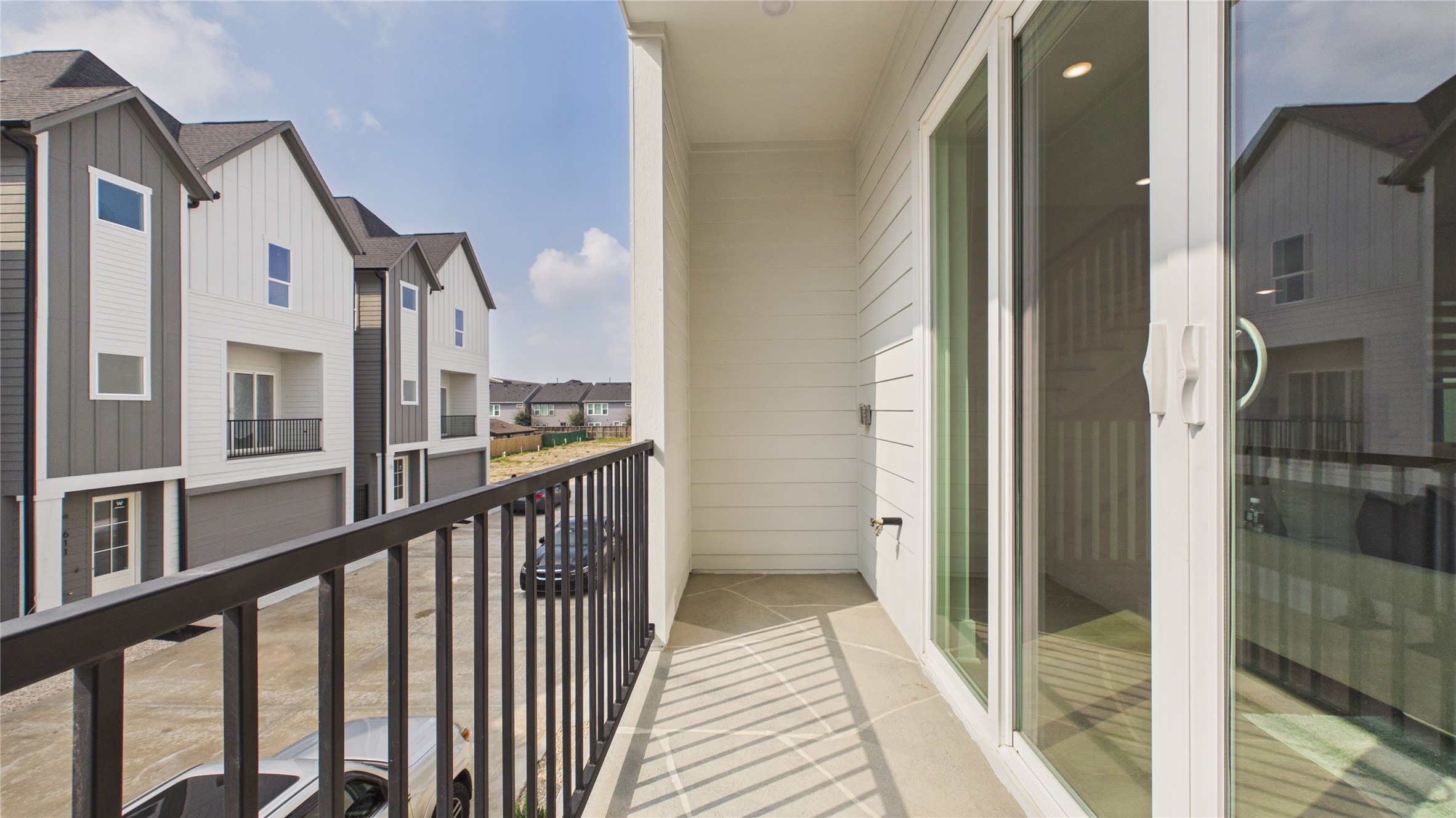 602 Skyland Terrace Way Houston, TX 77009 - Photo 19 of 40 This photo shows a modern balcony with sleek railing overlooking a row of contemporary townhouses. The area is bright, with sliding glass doors providing access from indoors, ideal for enjoying fresh air and views of the neighborhood.