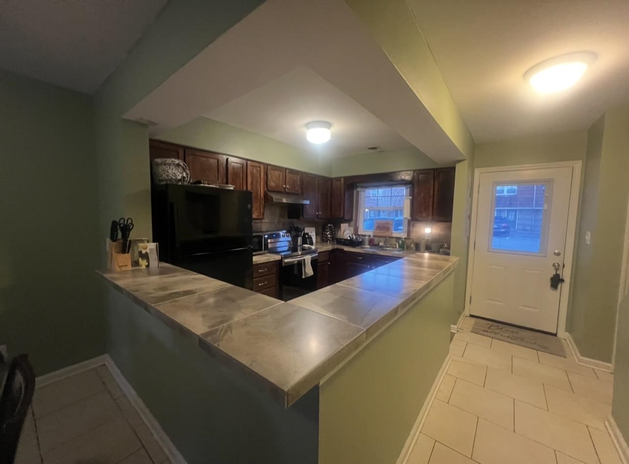 1025 Carolina Road, Unit O1 Conway, SC 29526 - Photo 3 of 18 Kitchen featuring freestanding refrigerator, dark brown cabinetry, stainless steel range with electric cooktop, light tile patterned floors, and a peninsula