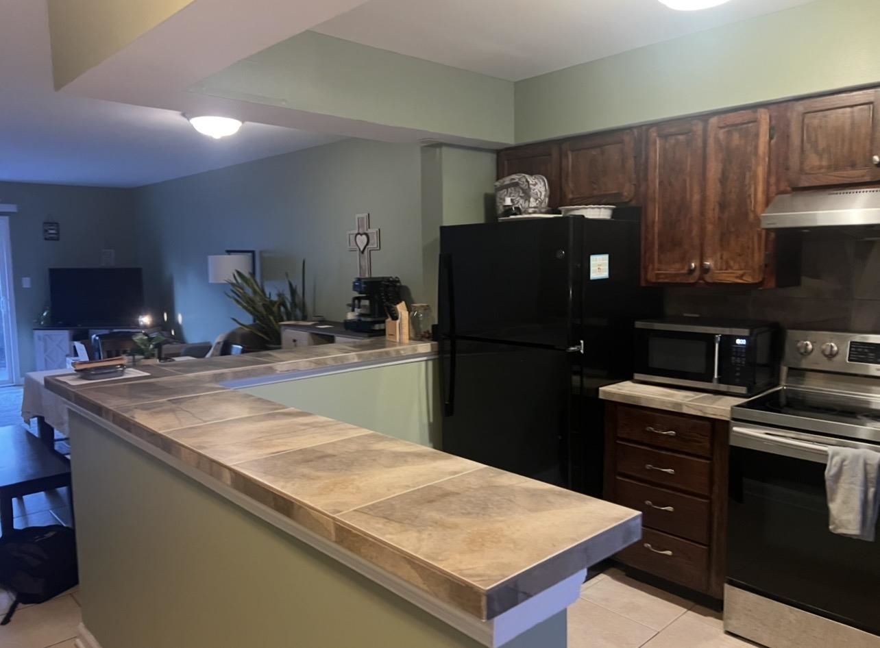 1025 Carolina Road, Unit O1 Conway, SC 29526 - Photo 18 of 18 Kitchen featuring appliances with stainless steel finishes, dark brown cabinets, light tile patterned flooring, open floor plan, and under cabinet range hood