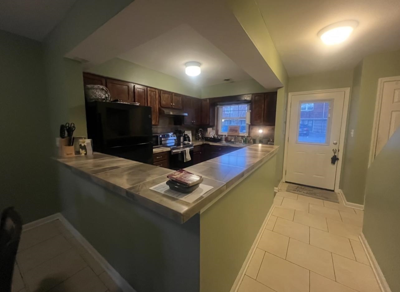 1025 Carolina Road, Unit O1 Conway, SC 29526 - Photo 6 of 18 Kitchen with freestanding refrigerator, dark brown cabinets, light tile patterned flooring, and a peninsula