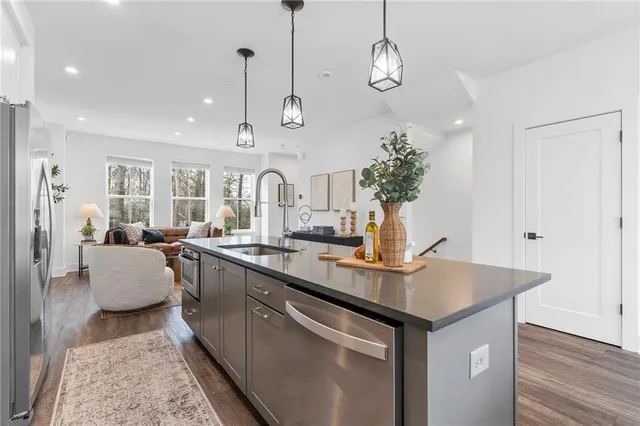 a open kitchen with stainless steel appliances granite countertop a sink a center island and living room view