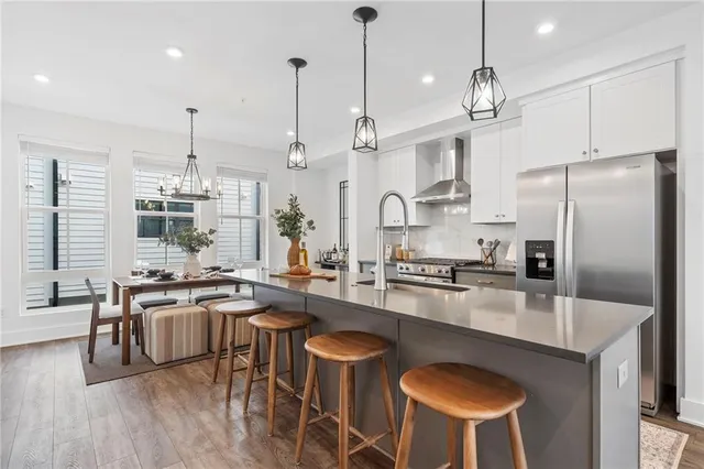 a kitchen with stainless steel appliances a table chairs stove and refrigerator